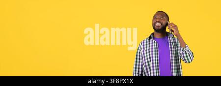 Happy Black Man Talking On Smartphone With Smile, Yellow Background Stock Photo