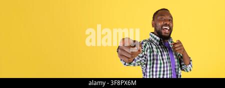 Happy Black Man Pointing And Smiling At Camera, Yellow Background, Positive Vibe Stock Photo