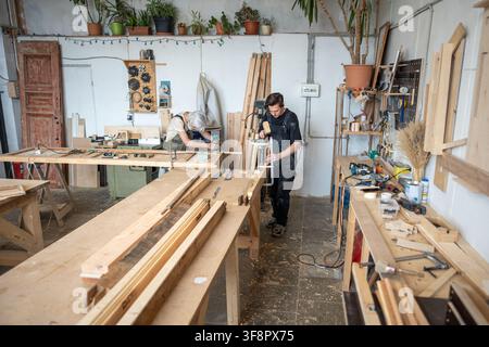 Men at work, qualified focused carpenters working at restoration workshop on wooden furniture repair Stock Photo