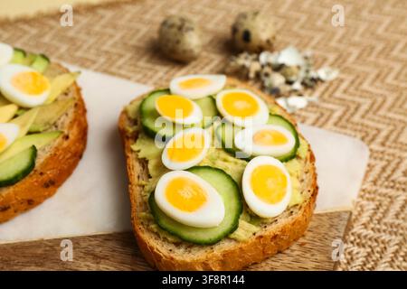 Tasty toasts with quail eggs, avocado and cucumber on table, closeup Stock Photo
