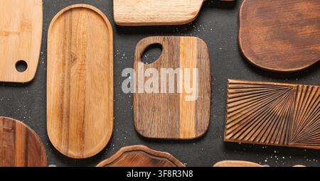 Various wooden cutting boards and serving platters with different shapes and wood grains on a dark background Stock Photo