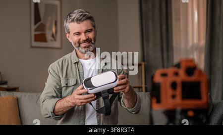 Smiling Senior Man Wearing Vr Headset Engaged In Virtual Reality Experience At Home, Technology Concept Stock Photo