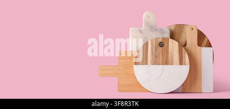 Assortment of wooden and marble cutting boards for kitchen and food preparation on a pink background Stock Photo