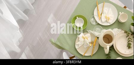 Elegant table setting with green tablecloth and gold cutlery, ready for a festive meal or special occasion Stock Photo