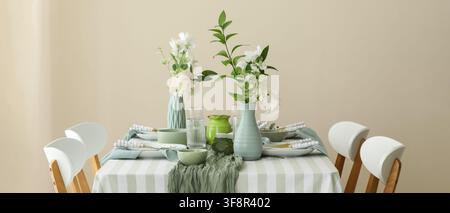Elegant dining table setting with white flowers in mint green vases and striped tablecloth for a spring celebration, the table is adorned with a strip Stock Photo