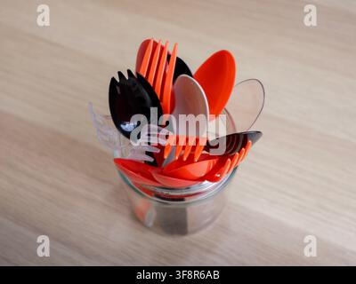 A jar of disposable plastic utensils from takout orders sitting on wooden tabletop Stock Photo