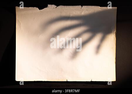 Vintage torn paper with creepy hand shadow for Halloween horror poster nightmare banner or invitation Stock Photo