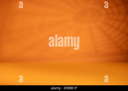 Empty orange Halloween background with soft spiderweb shadow and copy space for product mockup poster or seasonal advertising Stock Photo