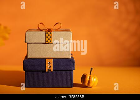 Stacked Halloween gift boxes with mini pumpkin on orange background for seasonal sale banner party invitation or retail promotion Stock Photo
