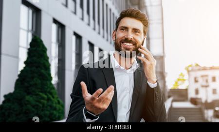 Smiling Young Man Talking On Phone In Business Attire, Urban Setting, Professional Concept Stock Photo