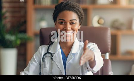 Smiling Black Female Doctor Offering Handshake In Office, Professional Healthcare Concept Stock Photo