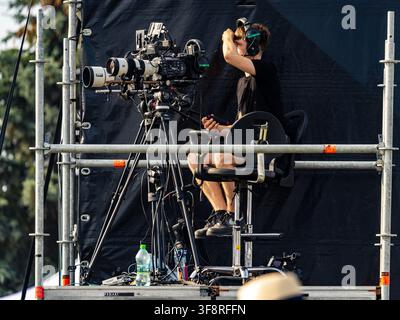 Camera operator filming a live concert stage from an elevated production platform Stock Photo