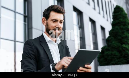 Confident Caucasian Man Using Tablet In Urban Office Setting, Business Concept Stock Photo