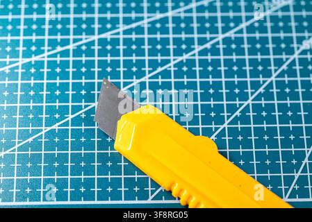 Detailed shot of a sharp utility blade over a green measuring mat in a studio setup Stock Photo