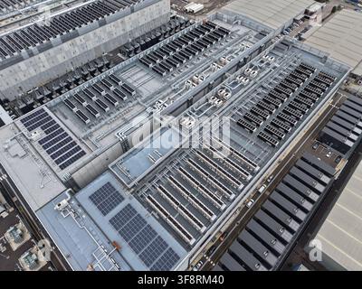 Large data center building featuring solar panels on the roof, alongside extensive cooling systems and industrial infrastructure Stock Photo