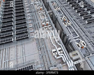 Large industrial facility roof showing intricate network of hvac systems, air conditioning units, pipes, and ductwork for cooling Stock Photo
