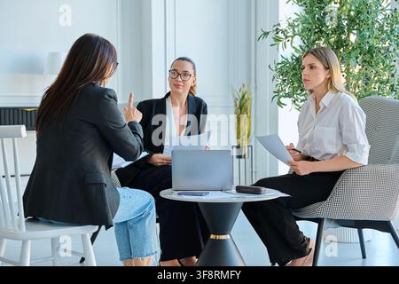 Group of diverse businesswomen discussing project documents during meeting in office Stock Photo