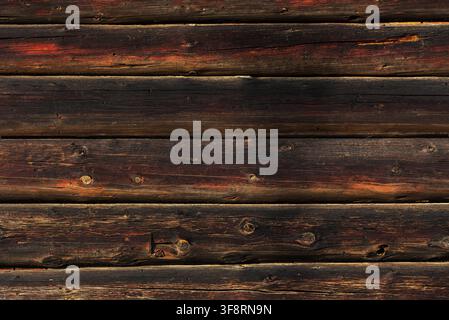 Weathered horizontal wooden planks show rich reddish-brown grain texture in warm directional light. Stock Photo
