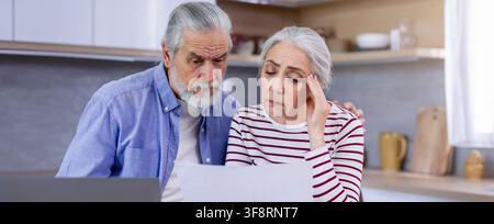 Worried Elderly Caucasian Couple Reviewing Financial Documents At Home, Healthcare Concept Stock Photo