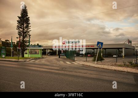 Loures, August 07 2021: Recheio supermarket building facade with entrance and parking lot under a cloudy sky. Stock Photo