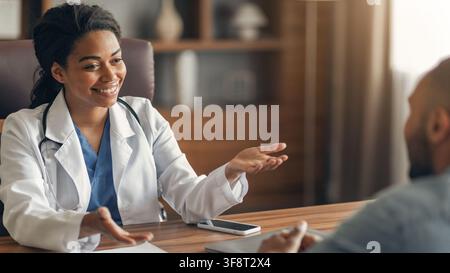 Smiling Black Female Doctor Talking To Patient In Office, Healthcare Concept Stock Photo