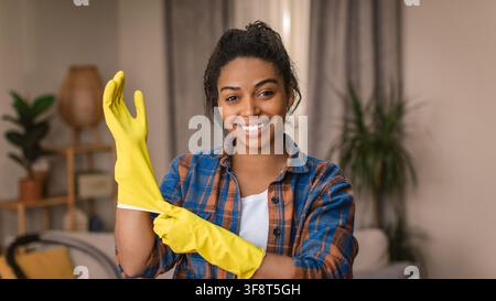 Smiling Young African American Woman Wearing Yellow Gloves Preparing To Clean Home Stock Photo