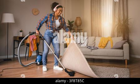 Smiling Black Woman Vacuuming Carpet At Home, Indoor Cleaning Concept Stock Photo