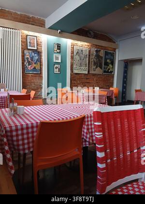 An empty cozy cafe or traditional restaurant dining room with wooden chairs and classic red and white checkered tablecloths. Stock Photo