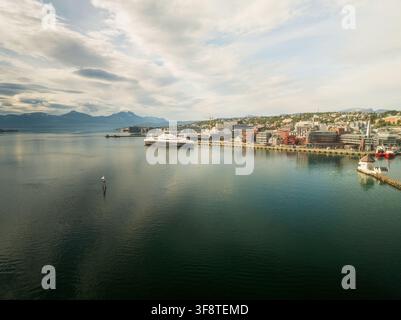 Aerial view of the harbor and cityscape of Tromso with a large cruise ship docked, surrounded by mountains under a cloudy sky in Tromso, Troms, Norway Stock Photo