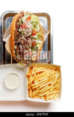 Doner kebab sandwich in sesame bun with french fries and sauce on tray Stock Photo