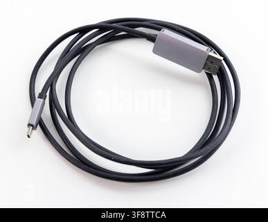 A coiled black data cable with grey connectors rests on a white background Stock Photo
