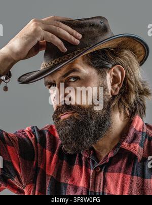 Man adjusting his cowboy hat. Man unshaven cowboys. American cowboy. Cowboy style in a plaid shirt Stock Photo