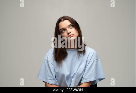 Young woman looking up, thinking and contemplating, feeling bored and pensive, having an idea or daydreaming Stock Photo