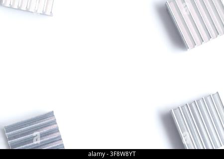 Four metallic corrugated pieces arranged in corners on white background. Clean, minimalist composition with geometric pattern. Ideal for architectural Stock Photo