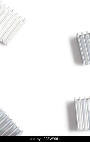Metal heat sinks arranged in corners on a clean white surface. Minimalist tech components suggest cooling, electronics, or engineering themes. Ideal f Stock Photo