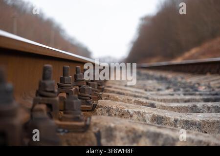 A close up view of rusted steel rail fastenings on weathered concrete sleepers in a rural setting, conveying strong themes of logistics, infrastructur Stock Photo