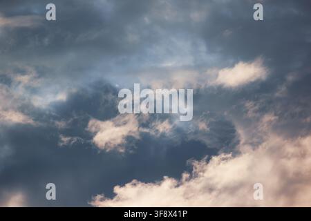 Dark storm clouds illuminated by warm golden sunlight during sunset Stock Photo