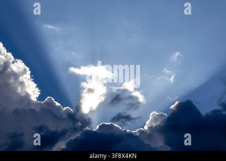 Dramatic God crepuscular rays streaming through dense dark storm clouds Stock Photo