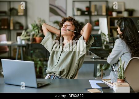 Diverse Women Working in Call Center and Stretching at Desk Stock Photo