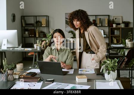 Diverse Women Collaborating on Laptop in Modern Office Stock Photo