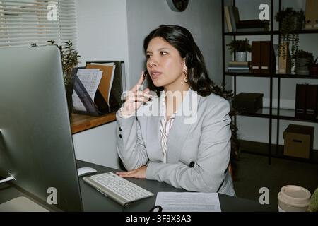 Hispanic Woman Wearing Headset Talking to Client on Computer Stock Photo