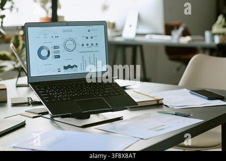 Laptop Displaying Financial Analytics on Desk in Modern Office Stock Photo