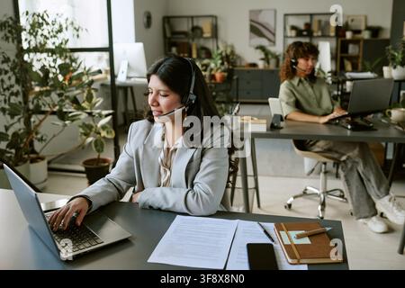 Diverse Female Operators Managing Customer Inquiries on Laptops Stock Photo