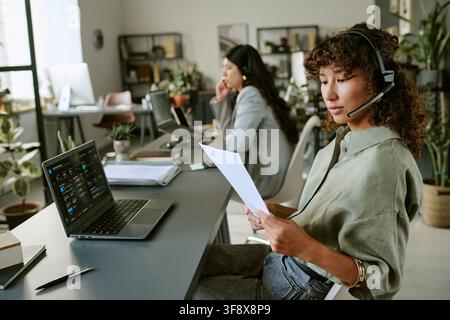 Diverse Female Agents Analyzing Data Sheets in Call Center Stock Photo