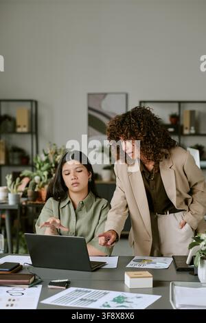 Diverse Female Colleagues Discussing Project on Laptop in Office Stock Photo