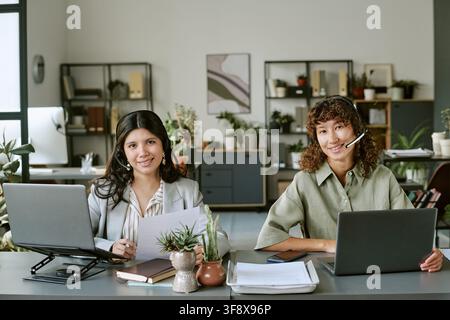 Portrait of Diverse Women Wearing Headsets and Working on Laptops Stock Photo