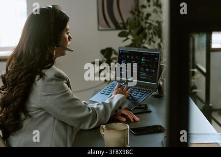 Hispanic Woman Working in Call Center Using Laptop and Headset Stock Photo