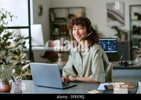 Portrait of Young Woman Working in Call Center Using Laptop Stock Photo