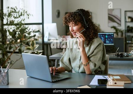 Biracial Woman Working in Call Center Using Laptop and Headset Stock Photo