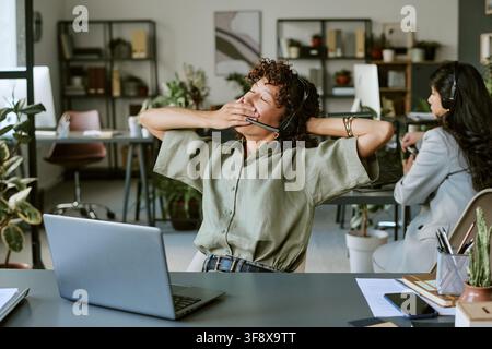 Tired Diverse Women Working in Call Center Stretching and Yawning Stock Photo